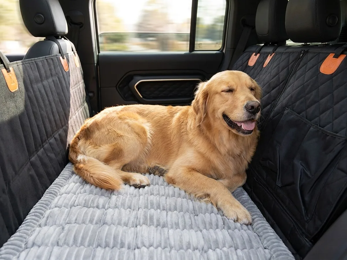 Golden retriever relaxing on the thick light-grey ribbed fleece mat covering a car back seat